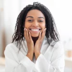 African woman smiling after using QNET's Physio Radiance Expert