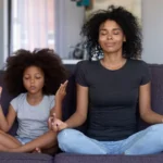 African mother and daughter meditating on a couch for World Health Day