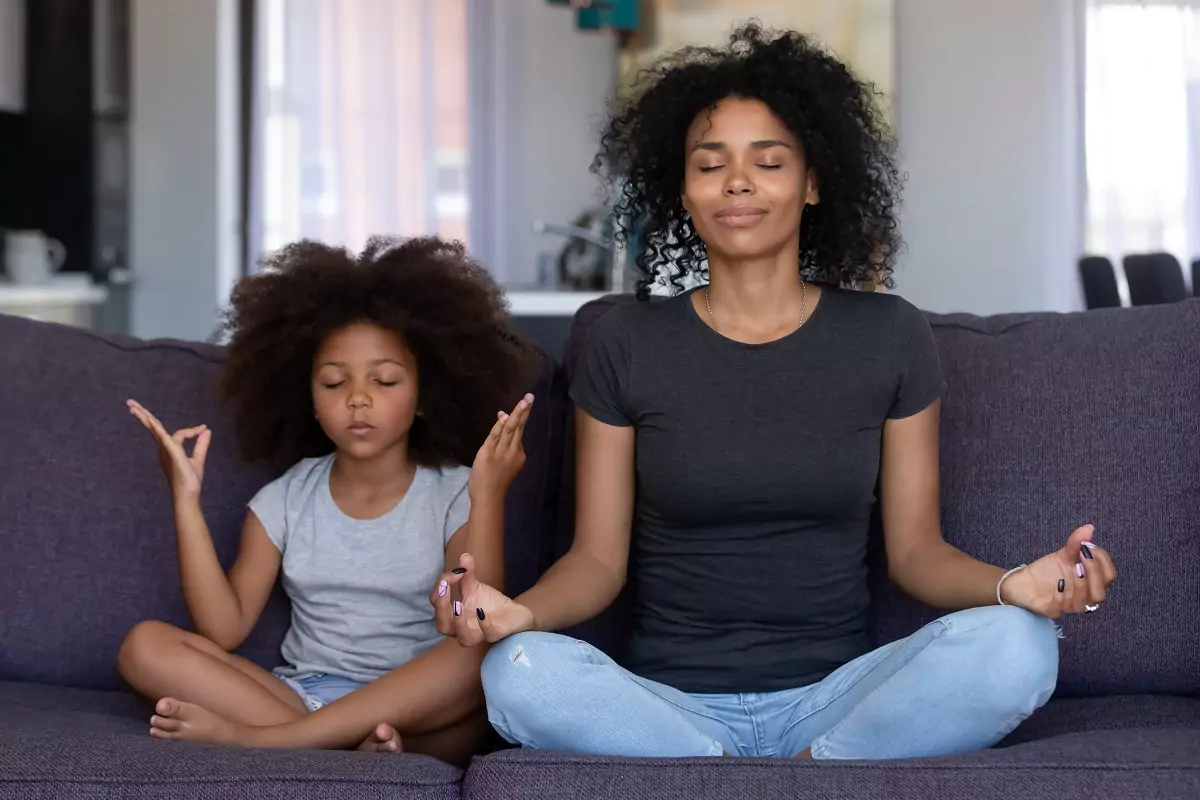 African mother and daughter meditating on a couch for World Health Day