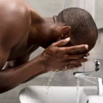 African man washing his face as part of his skincare routine