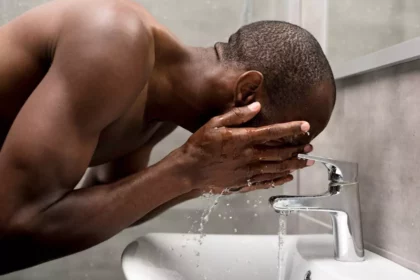 African man washing his face as part of his skincare routine