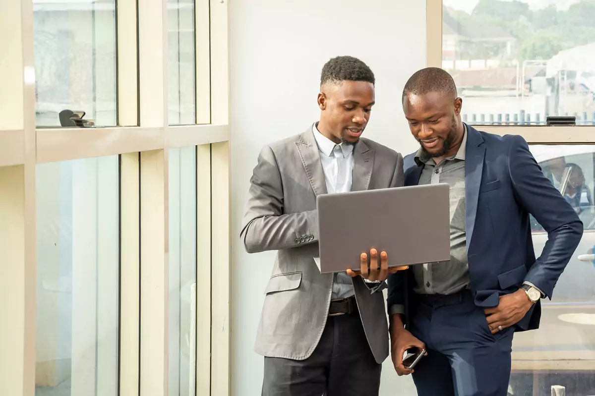 Two African men talking and looking at a laptop